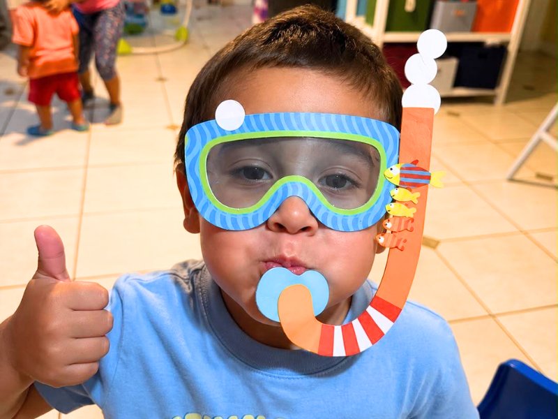 Child in a handmade snorkel craft giving a thumbs up