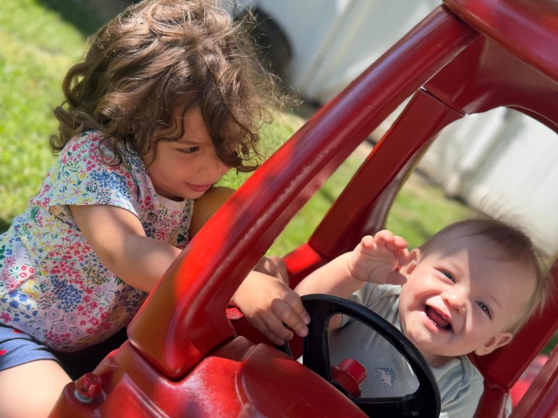 Two children laughing together in a toy car